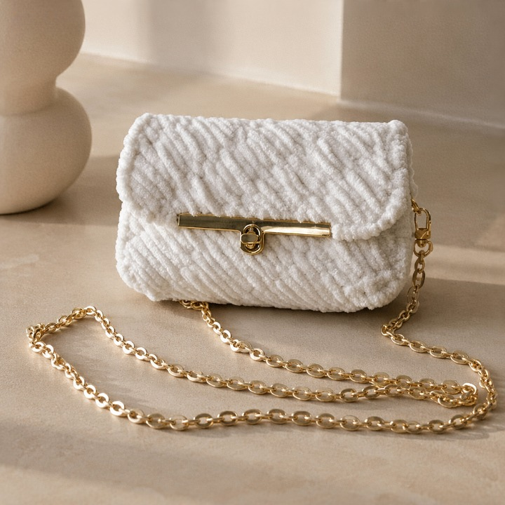 Handgefertigte weiße Umhängetasche Mini Eden mit weicher Häkelstruktur, goldener Schulterkette und elegantem Drehverschluss.